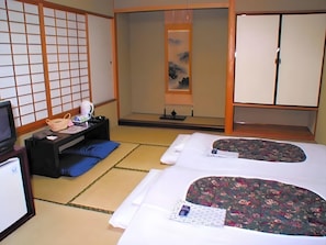 A traditional Japanese room with tatami flooring, a futon bed, a desk with a lamp, a television, and sliding doors. - Hotel Satoh Tokyo (Tokyo)