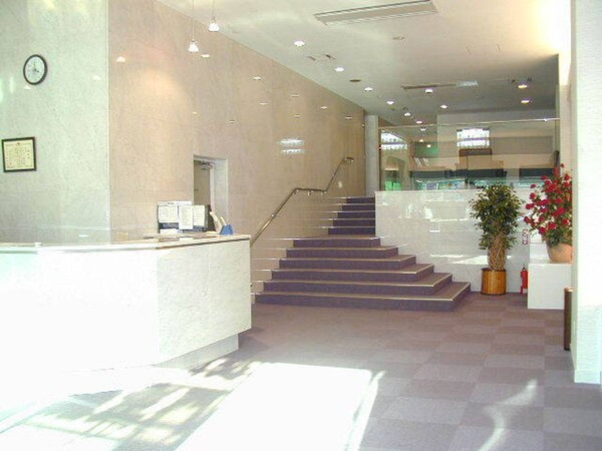 A reception area with a staircase, a reception desk, and a clock on the wall.