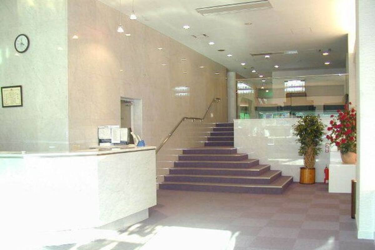 A reception area with a staircase, a reception desk, and a clock on the wall.