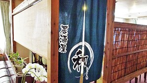 Un interior japonés tradicional con suelo de tatami, un panel shoji y una cuerda shimenawa colgada.