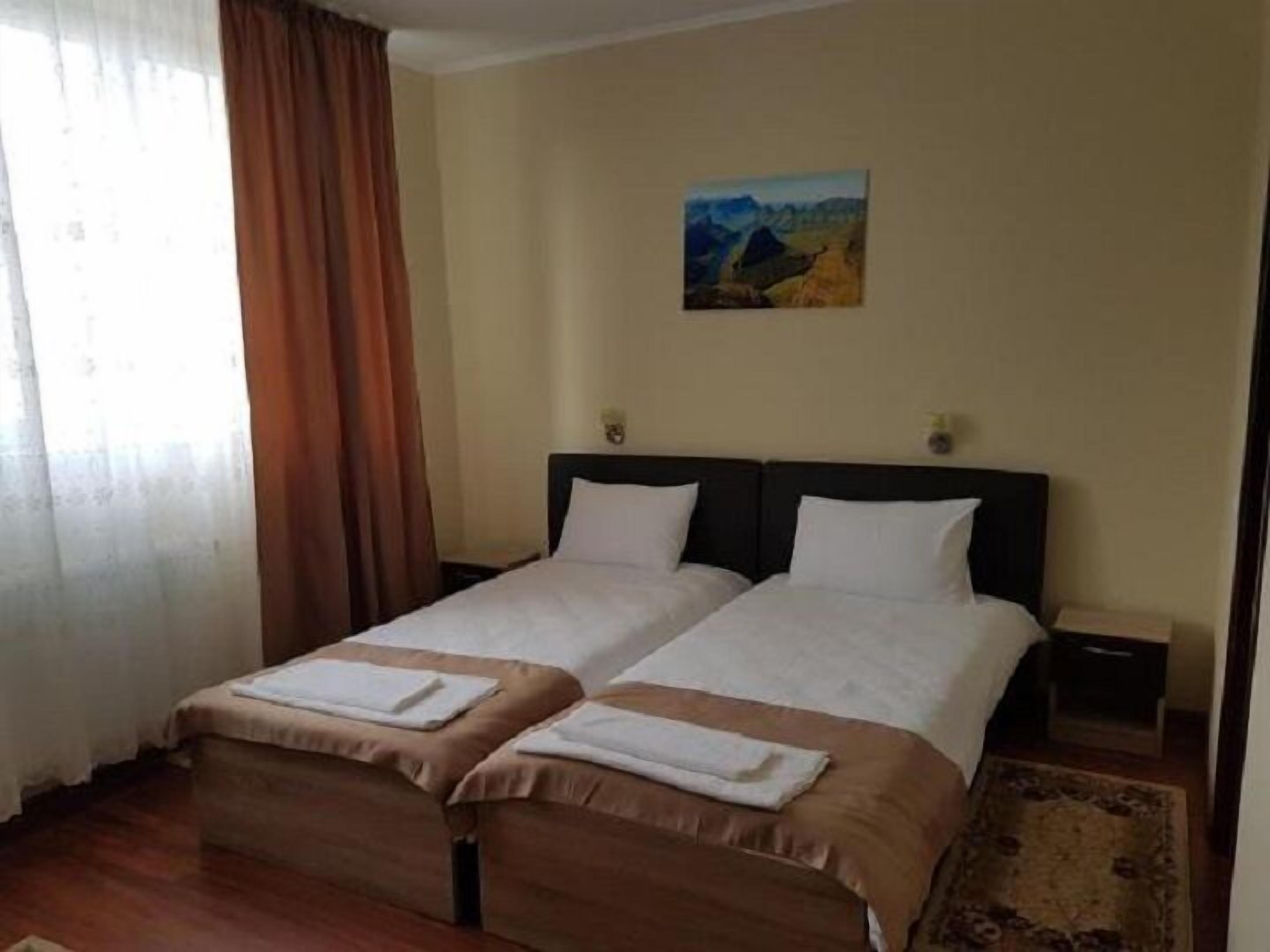 Habitación de hotel con dos camas, un cuadro en la pared y una ventana con cortinas.