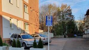A parking sign for Hotel New, a building with multiple windows, and two parked cars. - Hotel New (Baia Mare)