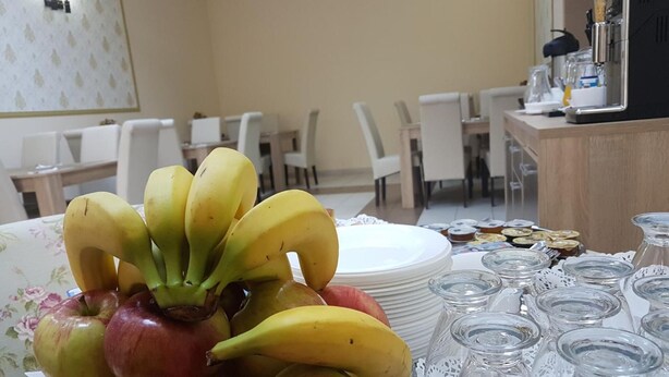 A table with a fruit arrangement, plates, and glassware in a dining area. - Hotel New (Baia Mare)