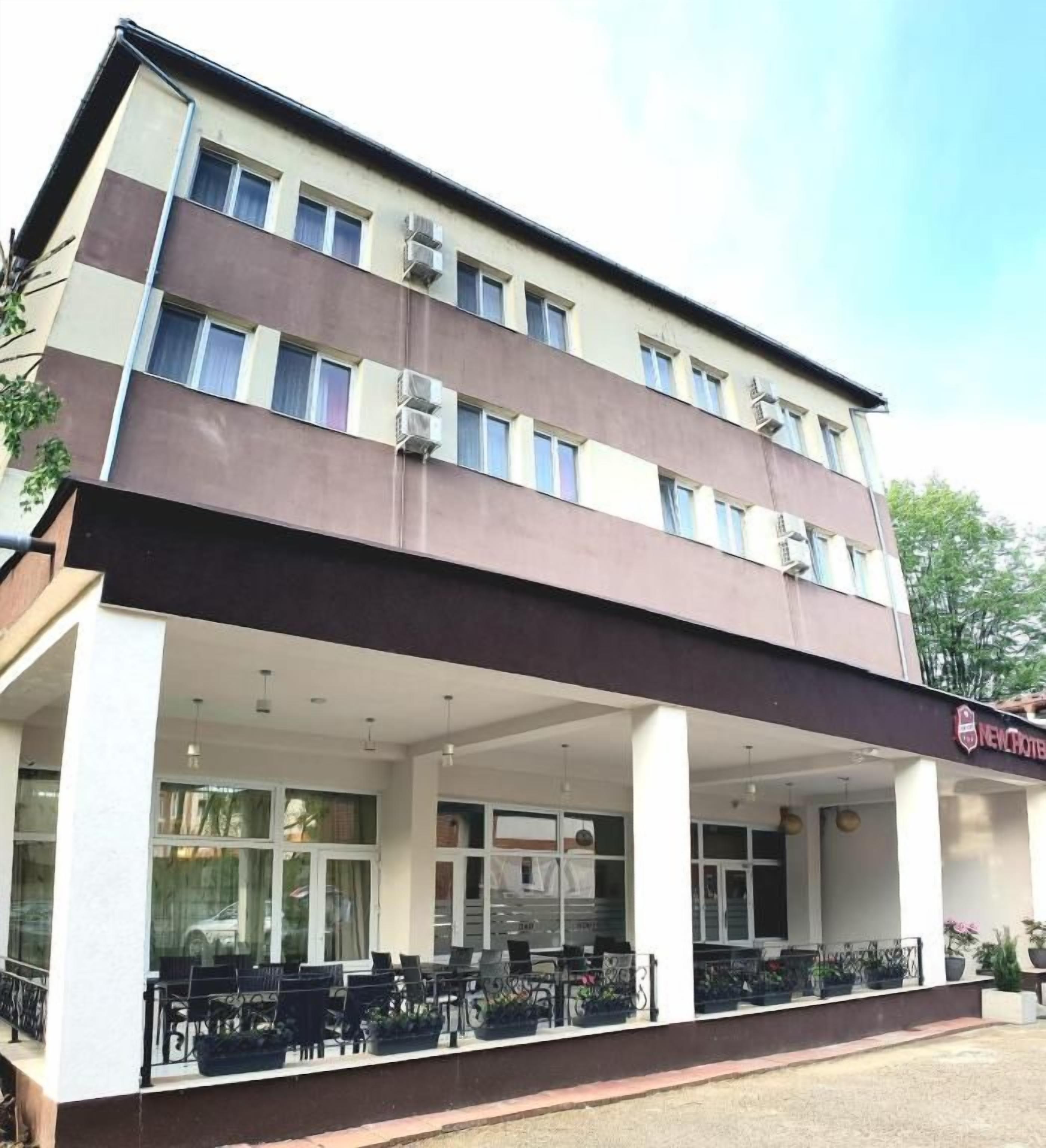 Un hotel de dos pisos con un área de estar al aire libre cubierta y un letrero que indica que es un hotel.