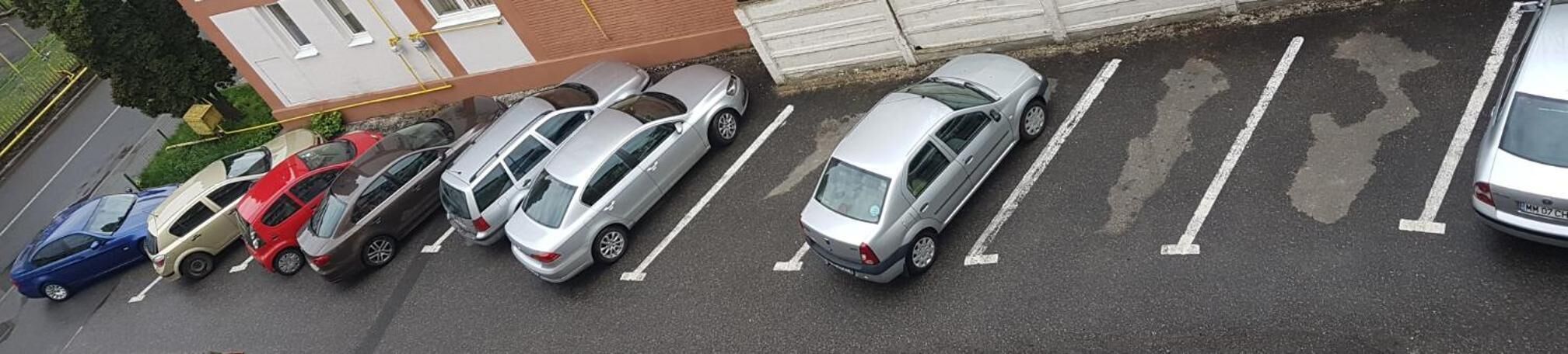 A parking lot with several cars parked in designated spaces.
