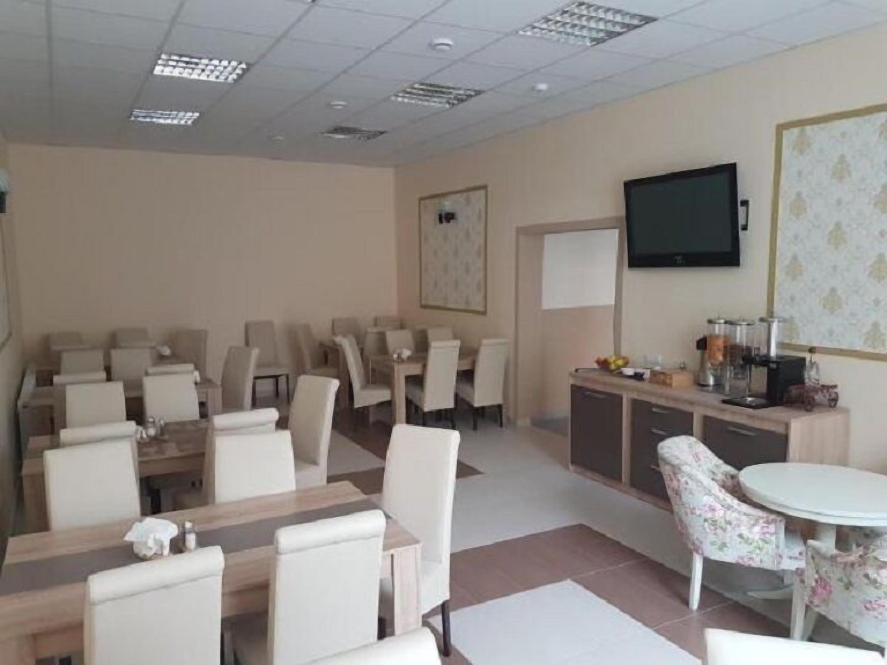 A hotel room with a dining area, a television mounted on the wall, and a small kitchenette.