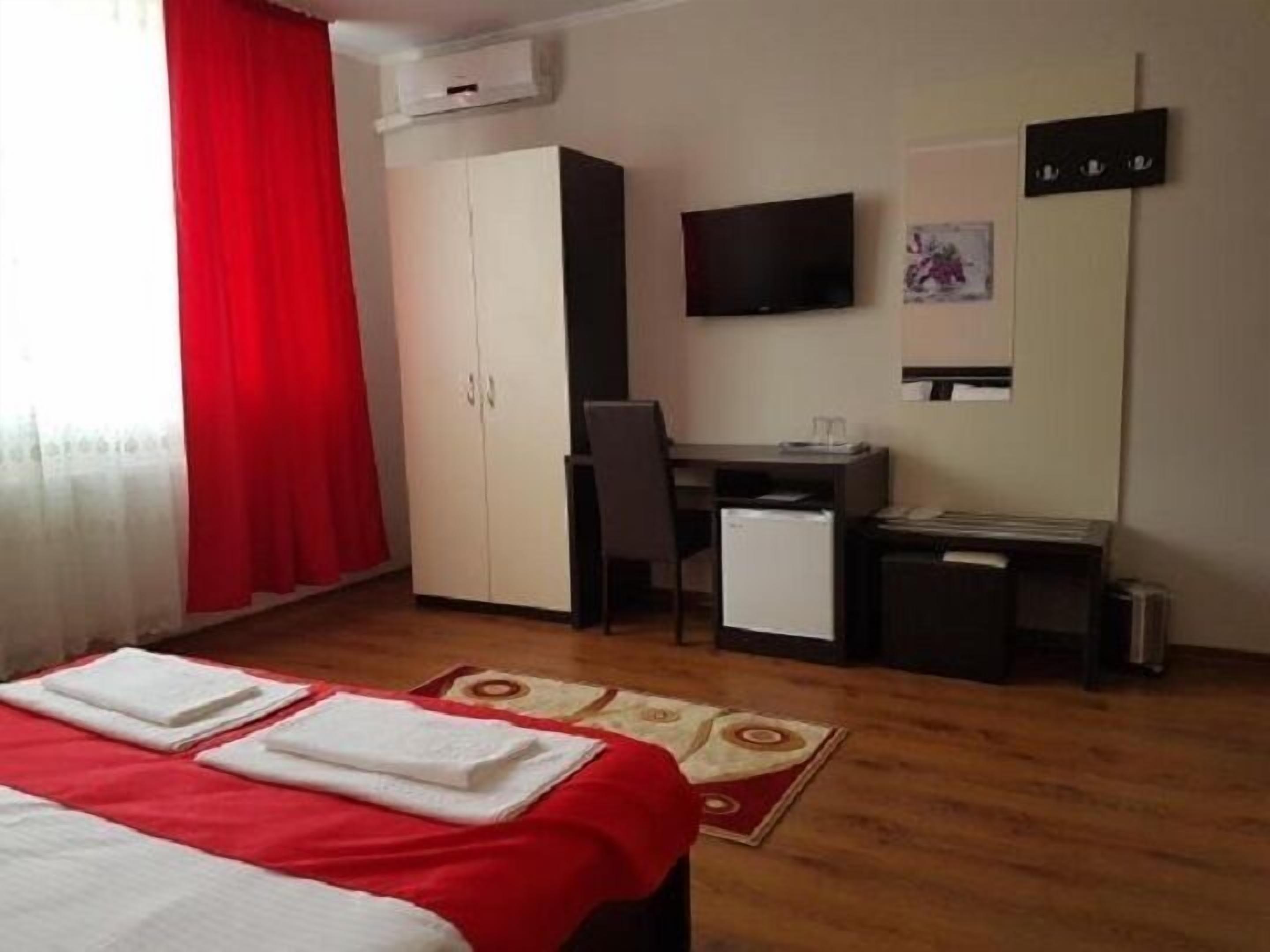 A hotel room with a bed, a desk, a chair, a TV, and a wardrobe.