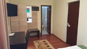 A hotel room with a bed, a desk, a TV, a wardrobe, and a bathroom door. - Hotel New (Baia Mare)