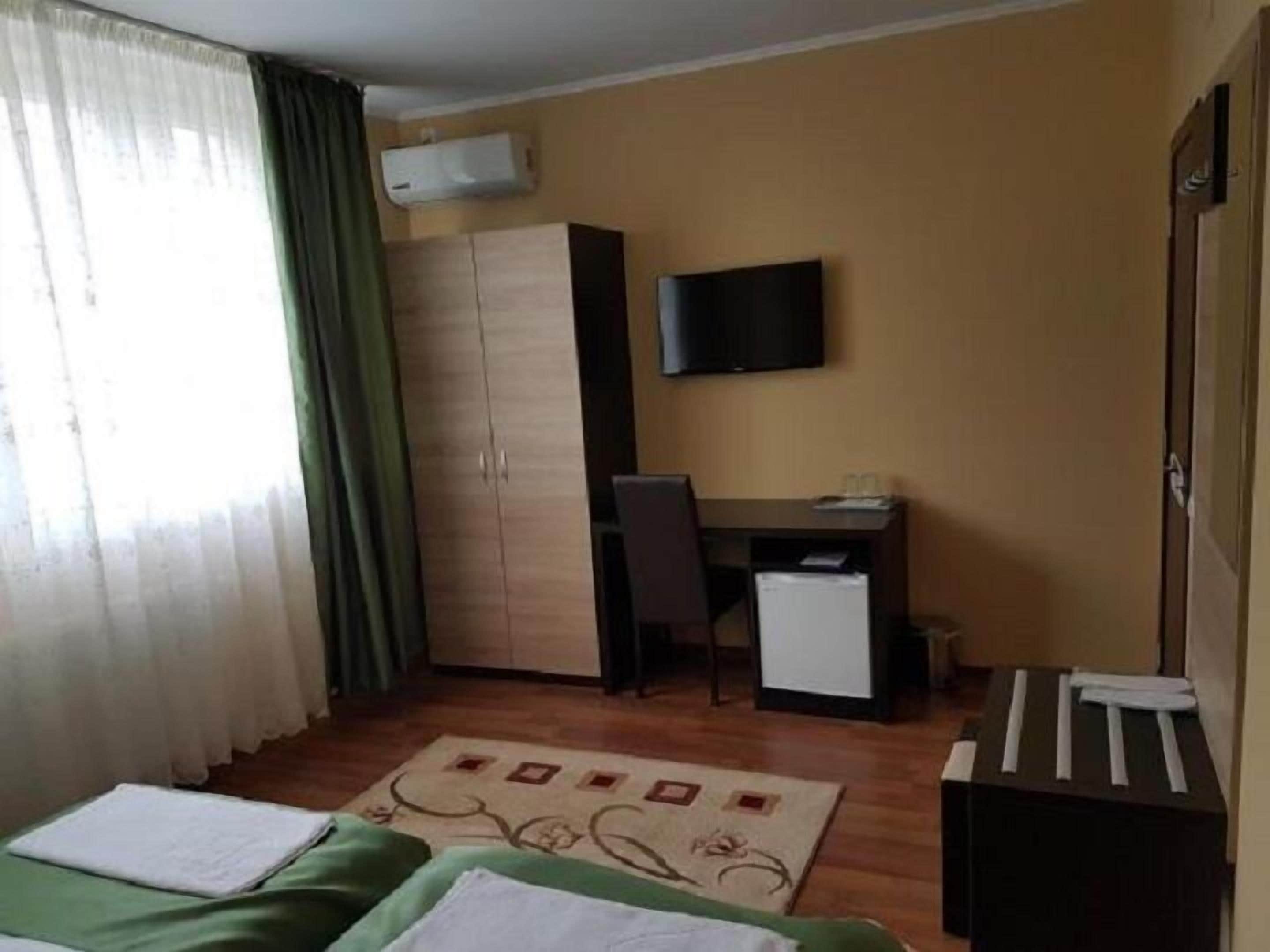 Una habitación de hotel con una cama, un escritorio, una silla, un televisor y un armario.