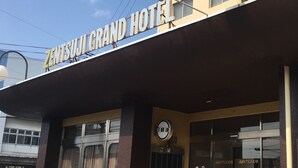 La façade du Grand Hôtel Zentsuji, avec une enseigne bien visible, une horloge et une entrée clairement identifiable.