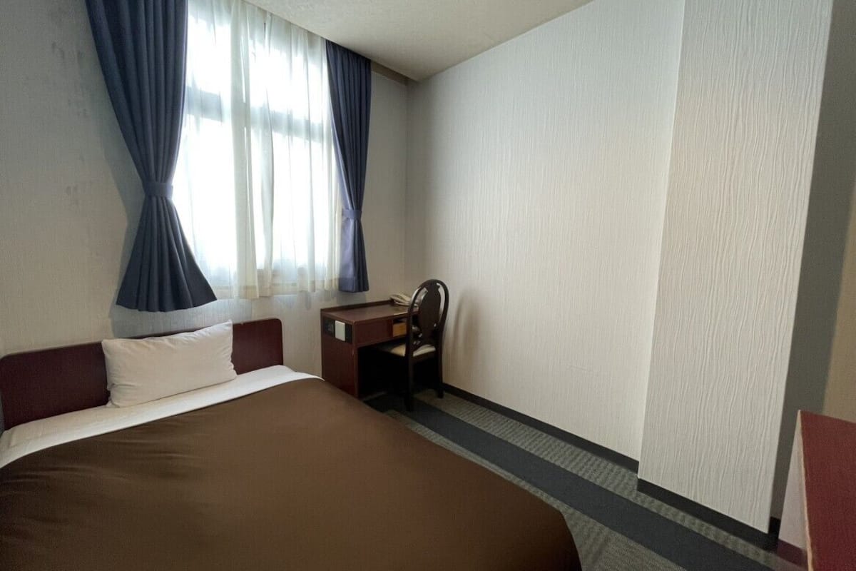 A hotel room with a large bed, a desk, and a chair.