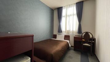Une chambre d’hôtel avec un lit, un bureau, une chaise et une petite table.