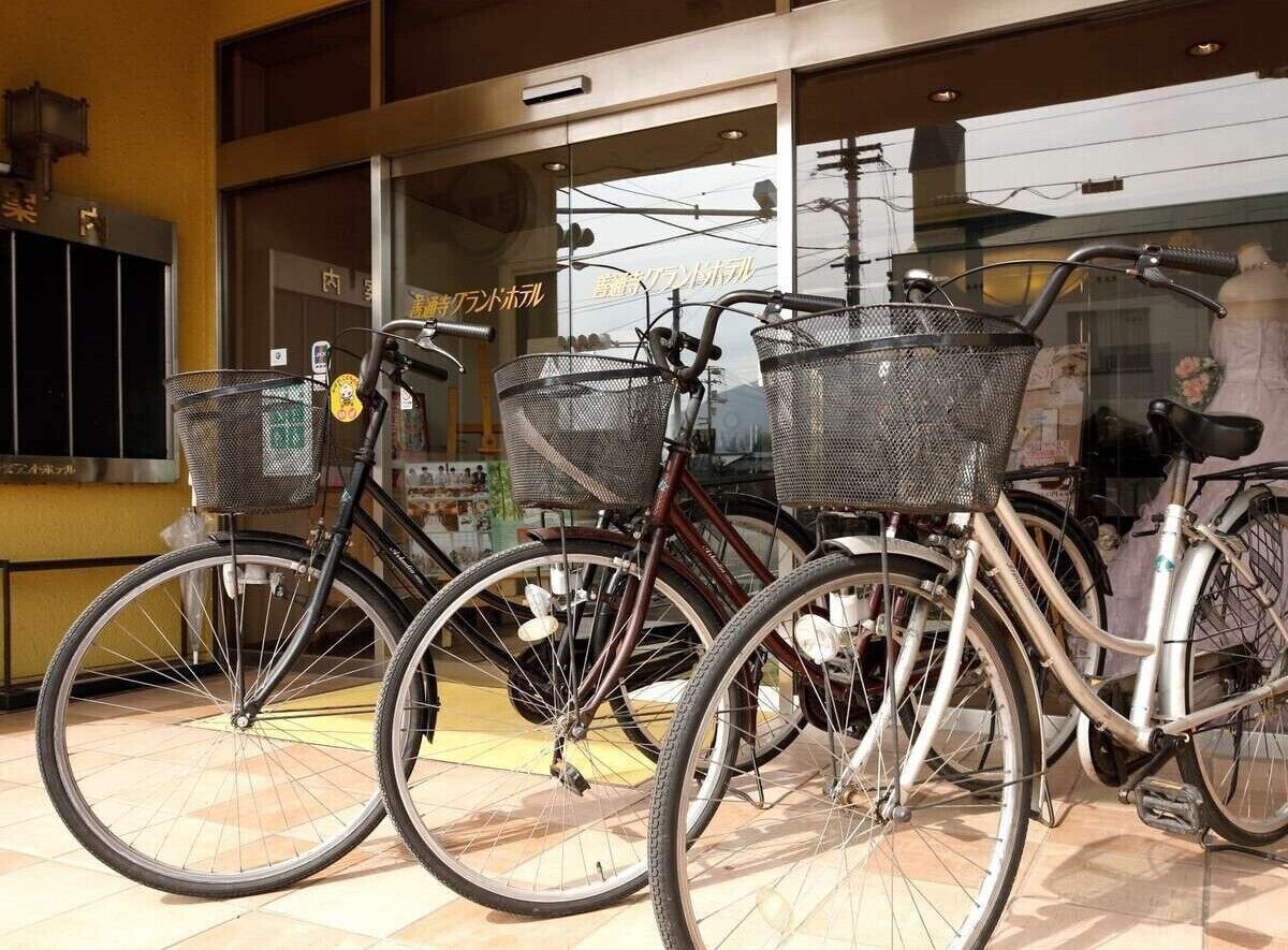 Tres bicicletas con cestas estacionadas frente a un edificio con ventanas amplias.
