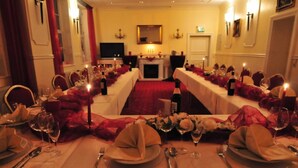 A formal dining room with long tables set for a meal, candles, and a fireplace in the background. - Double room 01 - Hotel Goldene Krone (Clausthal-Zellerfeld)
