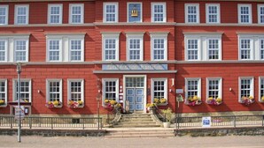 A red building with white trim, a central entrance, and flower boxes on the windows. - Double room 01 - Hotel Goldene Krone (Clausthal-Zellerfeld)