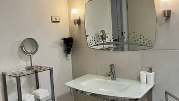 A modern bathroom with a white sink, a round mirror, and a towel rack with neatly folded towels.