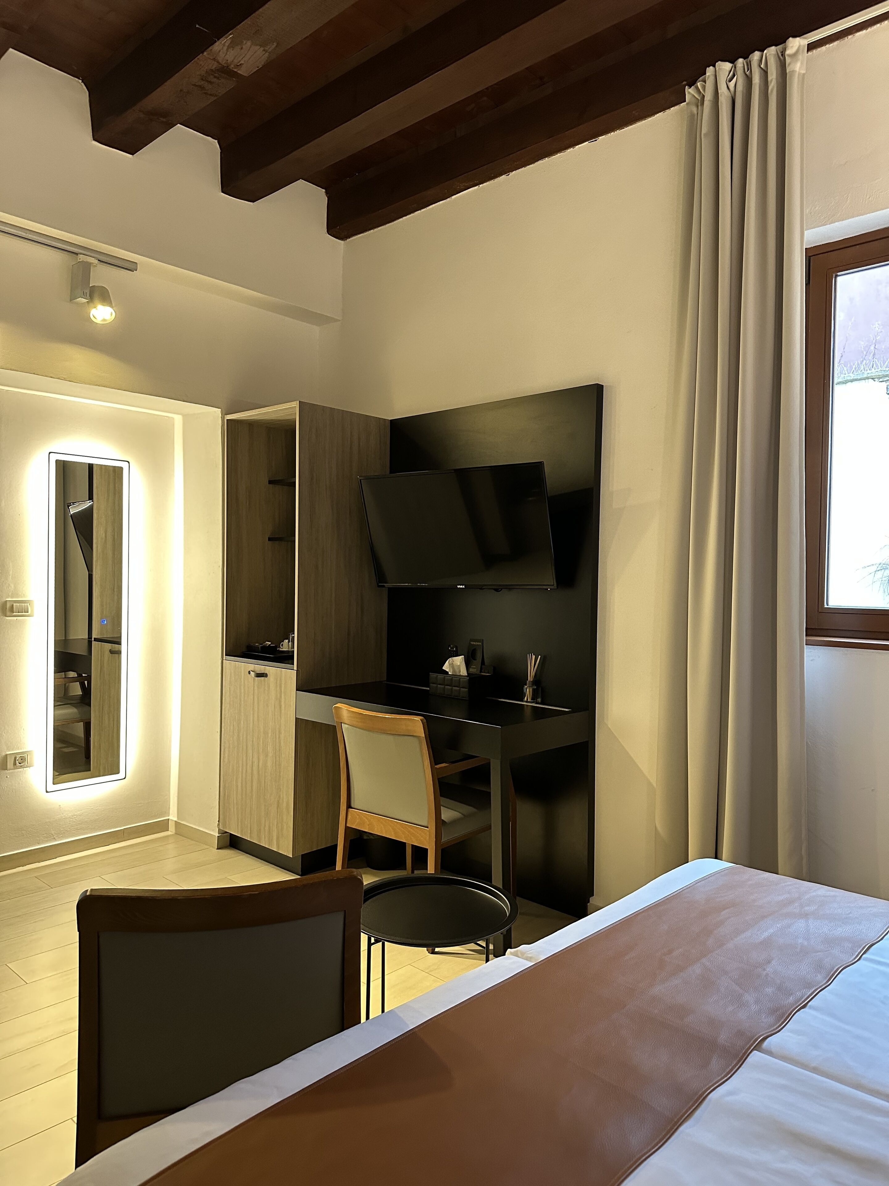 A modern bedroom with a bed, a desk, a chair, a TV, and a wardrobe.