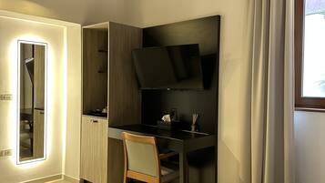 A modern bedroom with a bed, a desk, a chair, a TV, and a wardrobe.
