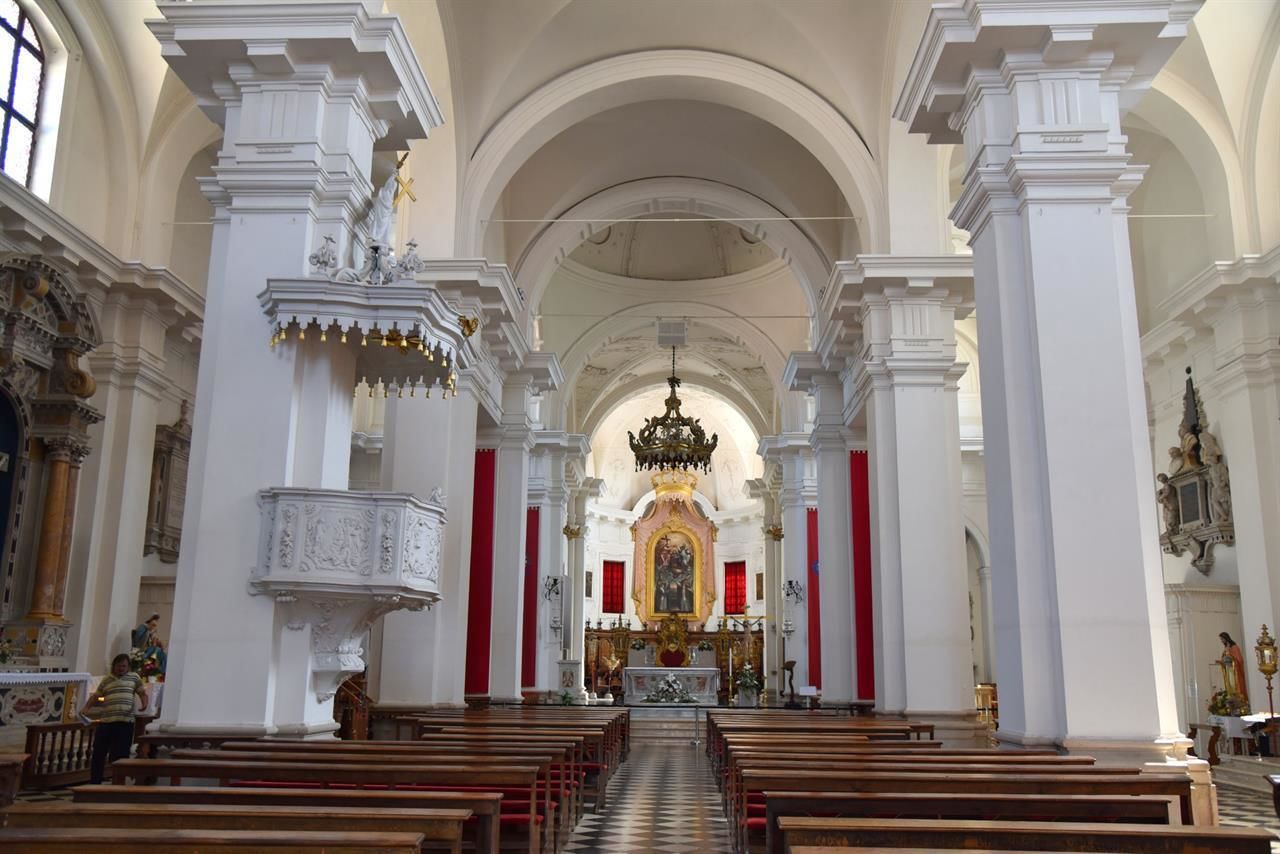 Een kerkinterieur met hoge plafonds, boogvensters en een centraal altaar.