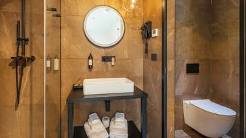 A modern bathroom with a built-in sink, a round mirror, a handheld showerhead, and a toilet.