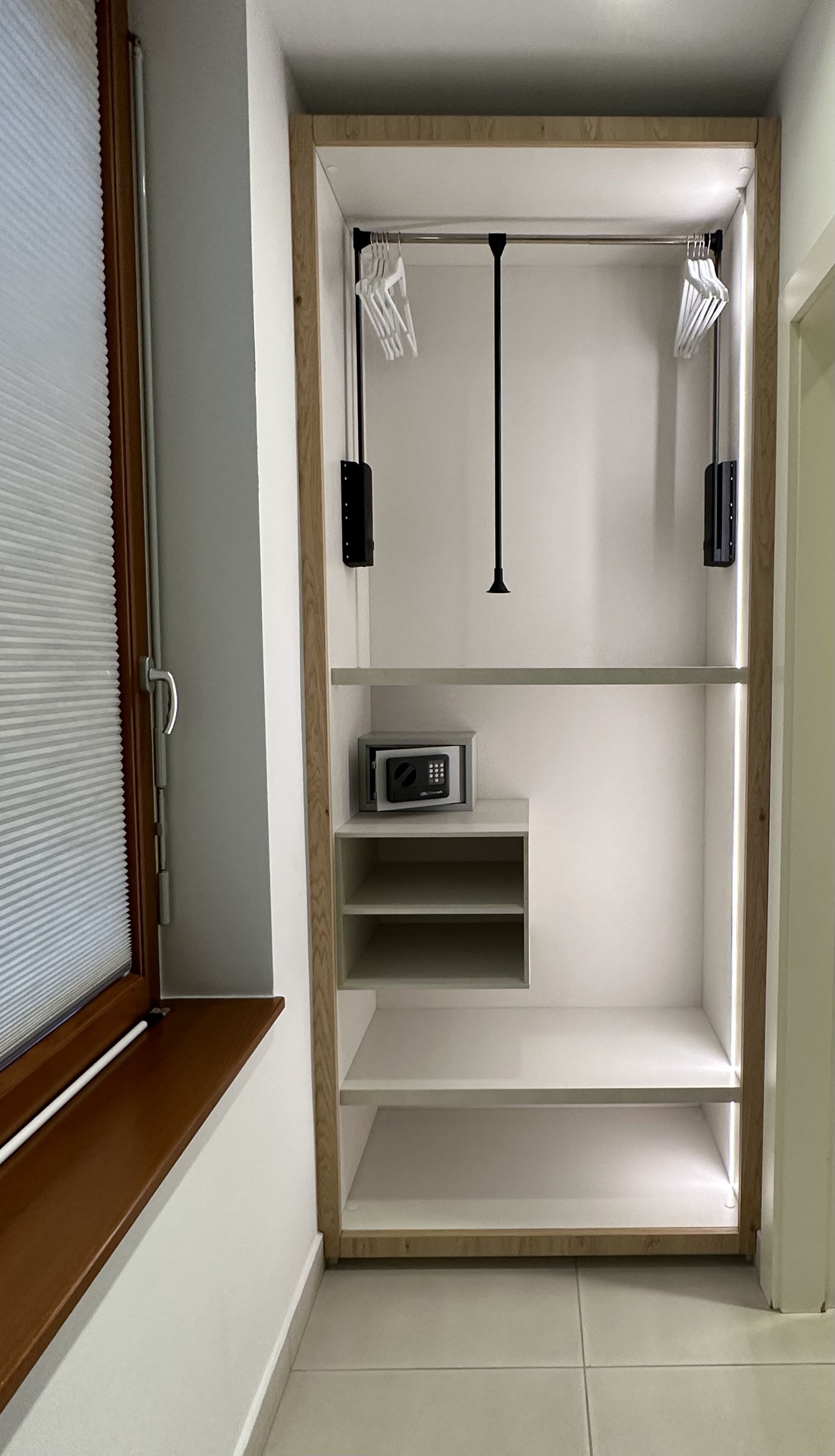 A narrow hallway with a built-in shelf unit, a microwave, and two pendant lights.