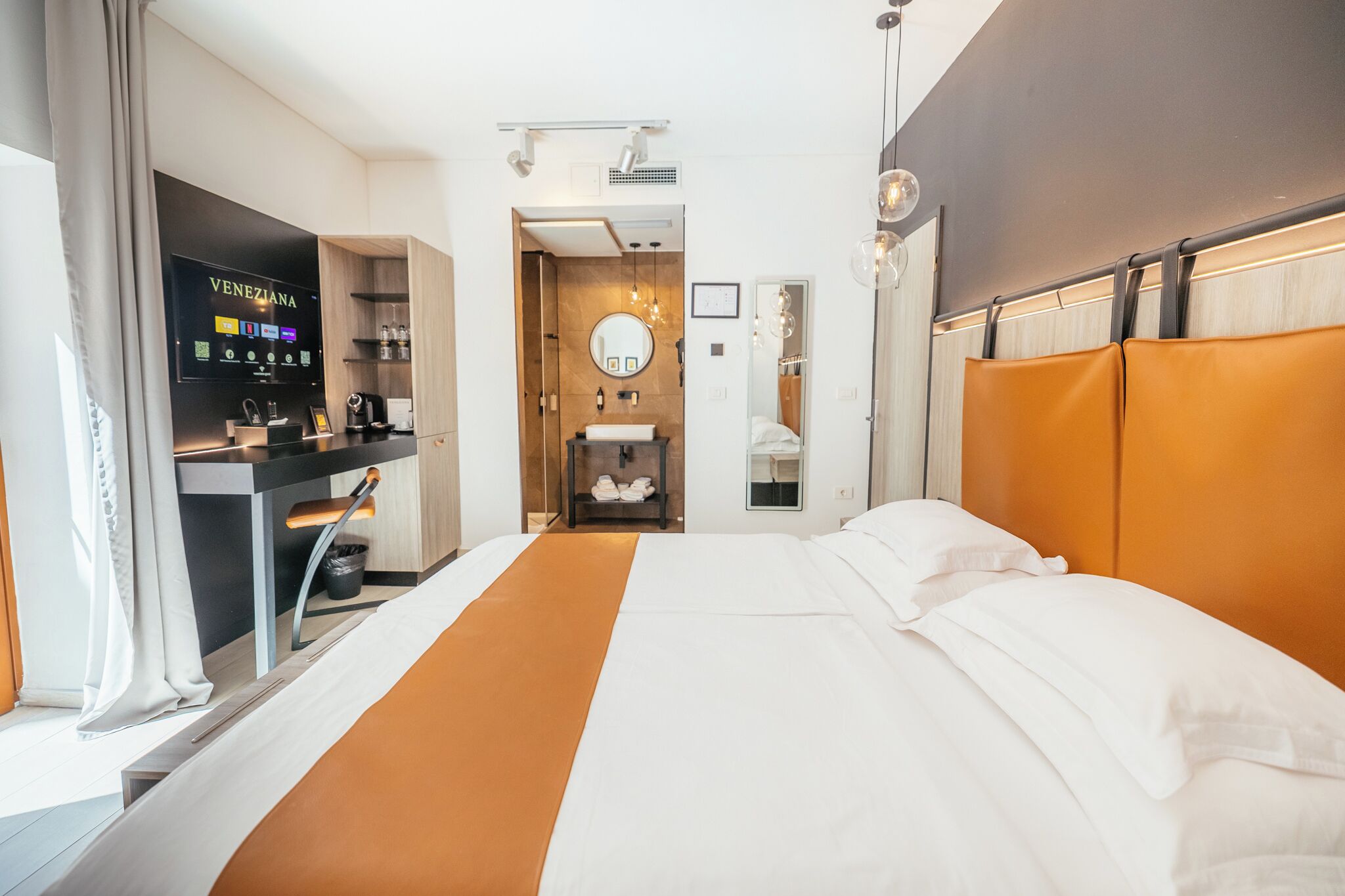 Ein Hotelzimmer mit Bett, Schreibtisch mit Fernseher, Badezimmer und Blick auf die Stadt.