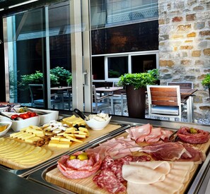 A charcuterie board with various meats and cheeses, a potted plant, and outdoor seating. - VENEZIANA Boutique Hotel Superior (Koper)