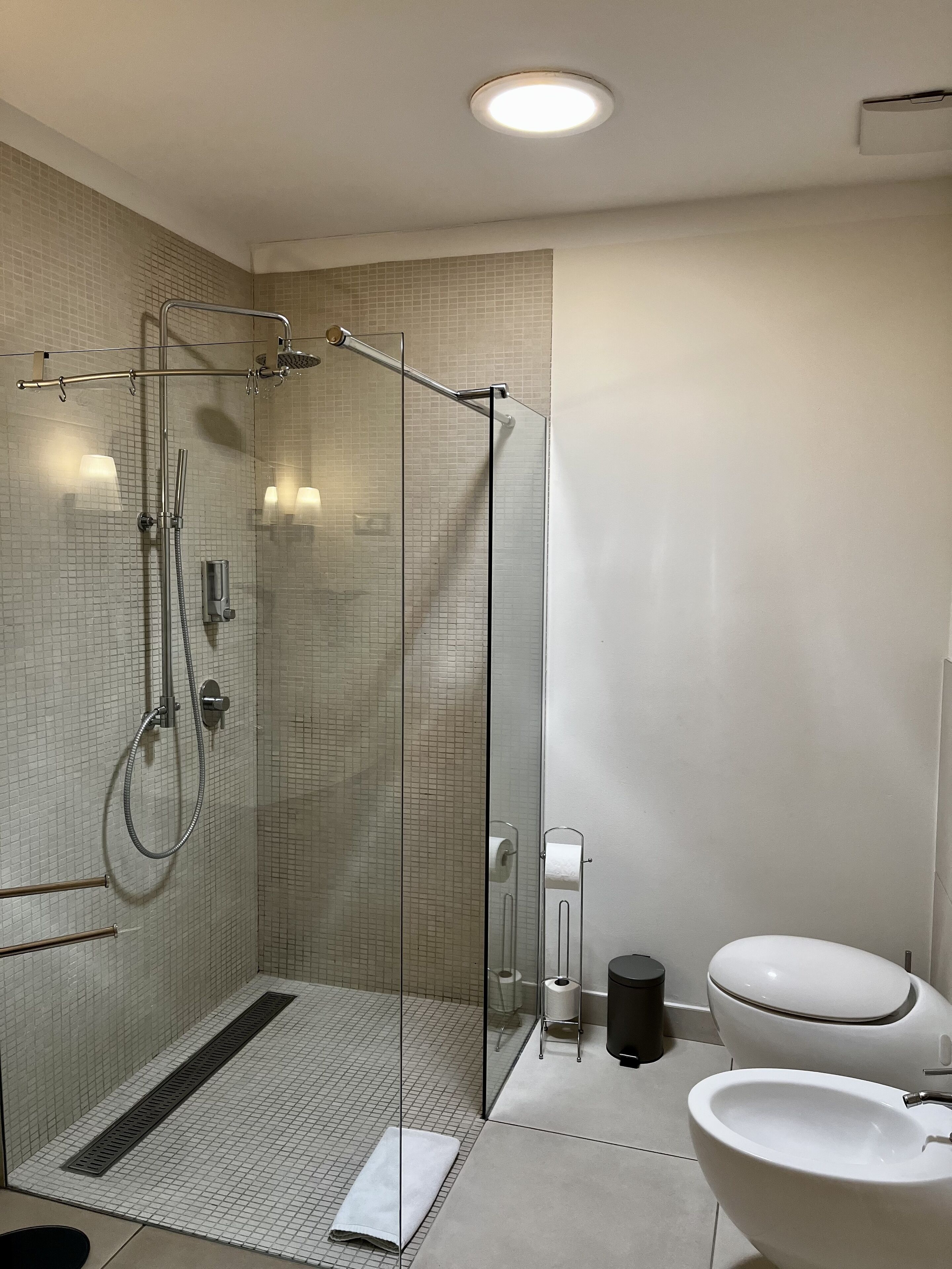 A modern bathroom with a glass-enclosed shower, a toilet, and a sink.