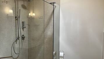 A modern bathroom with a glass-enclosed shower, a toilet, and a sink.