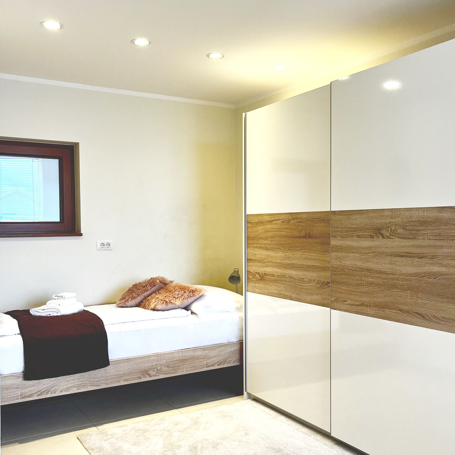 Ein Schlafzimmer mit Bett, Kleiderschrank und Fenster.