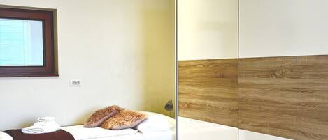 A bedroom with a bed, a wardrobe, and a window.