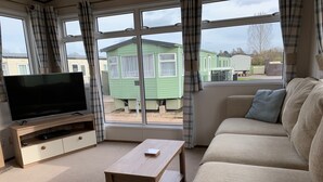 A living room with a television, sofa, and a small table. - Beautiful 2-bed Caravan in Stratford-upon-avon (Stratford-upon-Avon)
