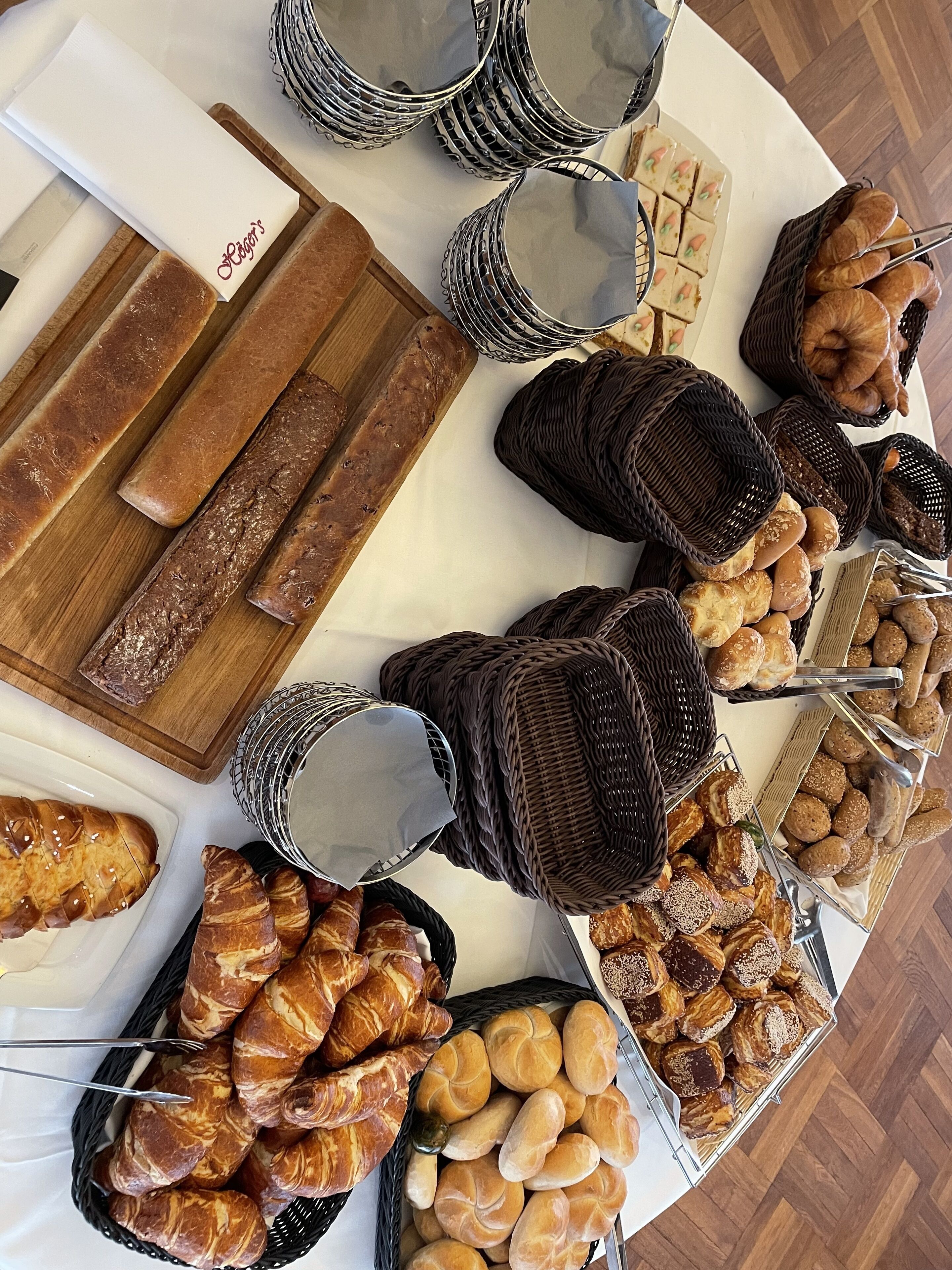 Une table de buffet proposant une variété de produits de boulangerie, notamment du pain, des viennoiseries et des petits pains.