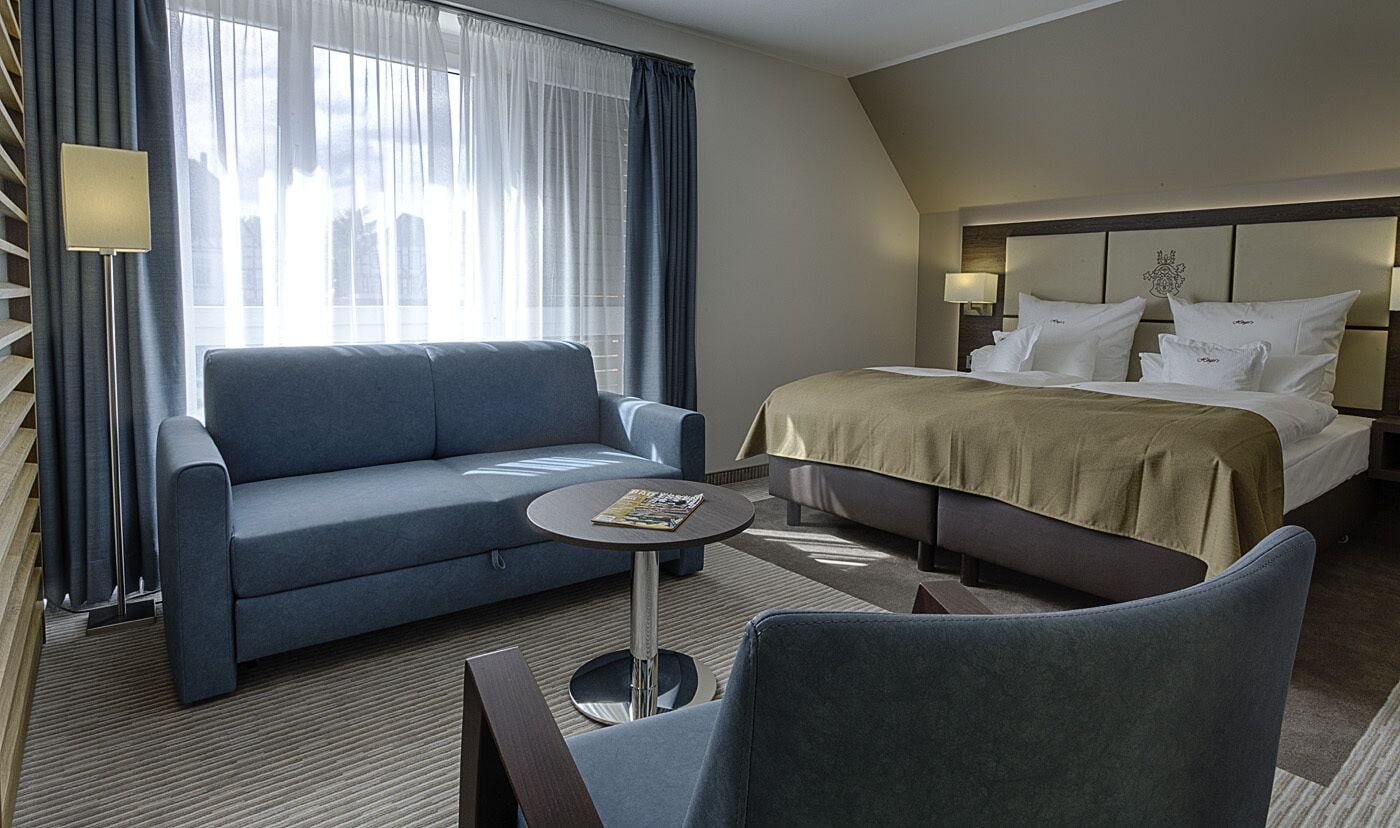 Una habitación de hotel con una cama, un sofá, una mesita y una silla.