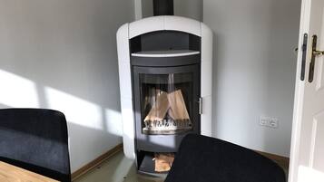 Una habitación moderna con una estufa de leña, una mesa de madera y sillas negras.