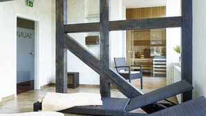 Un intérieur moderne avec un escalier en bois, des fauteuils confortables et une salle de bain ouverte dotée d’un porte-serviettes.