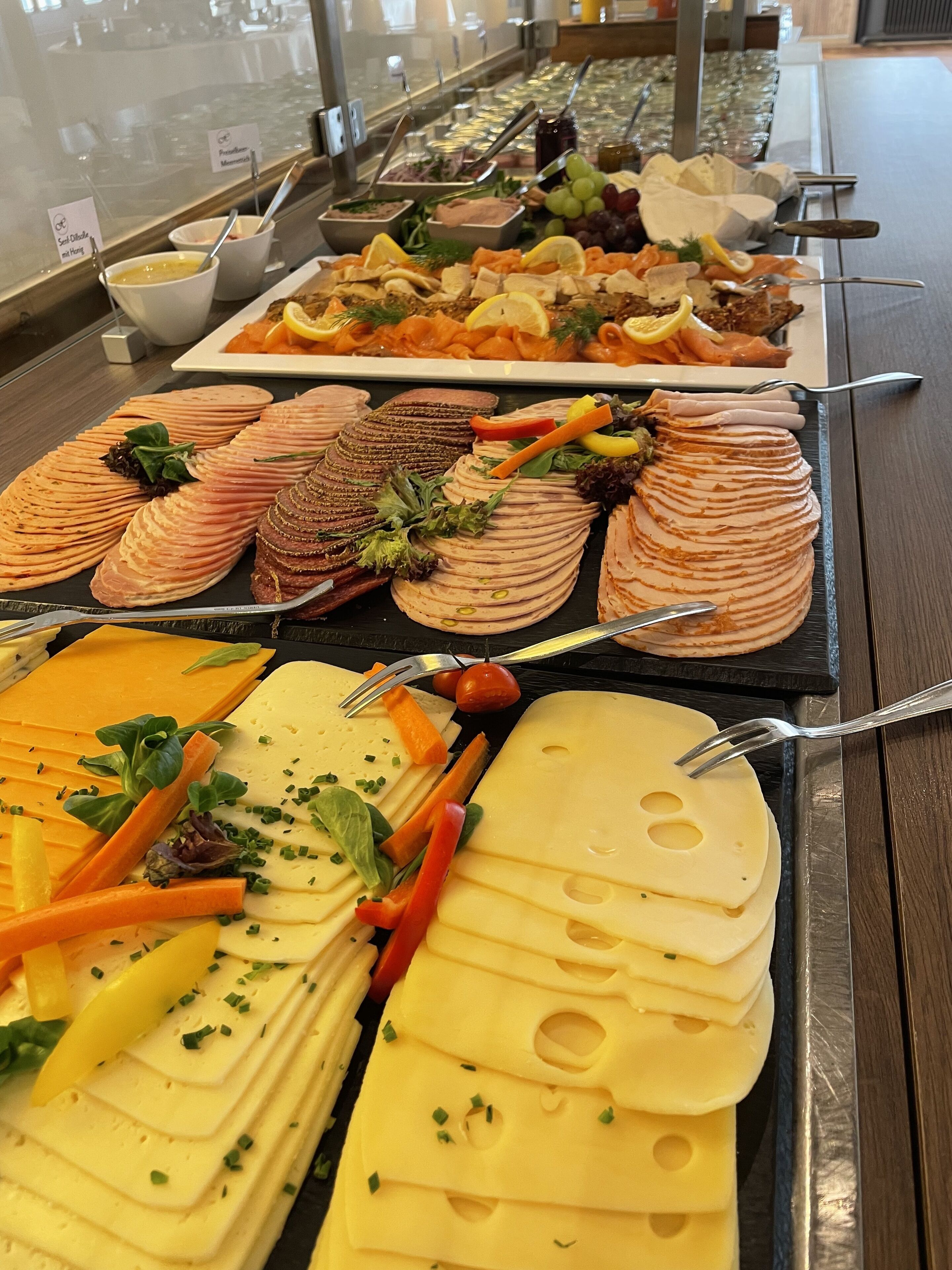 A buffet with various food items including sliced meats, cheeses, and vegetables.