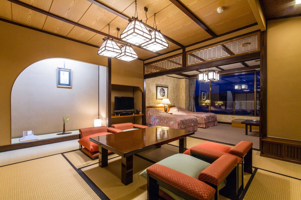 A traditional Japanese-style room with tatami flooring, a low table, and red cushions.