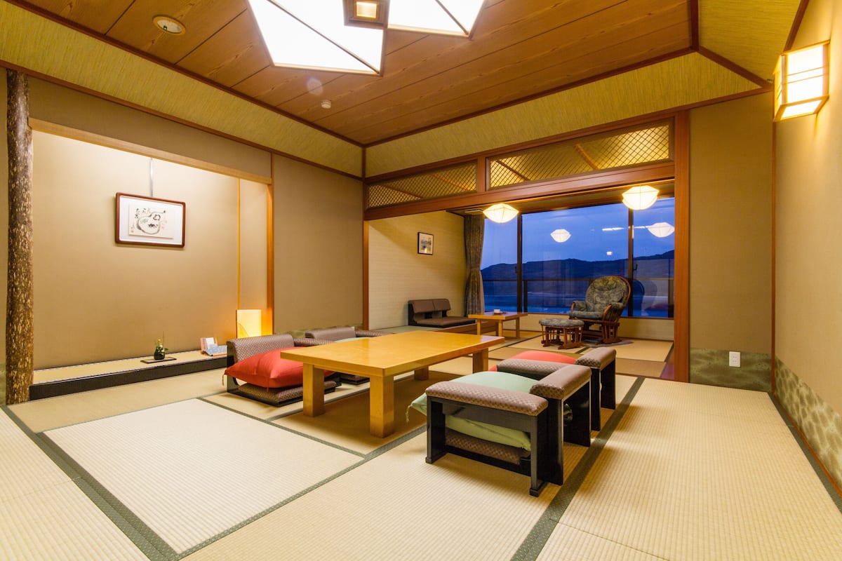 A traditional Japanese room with tatami flooring, a wooden table, and a view of the night sky.