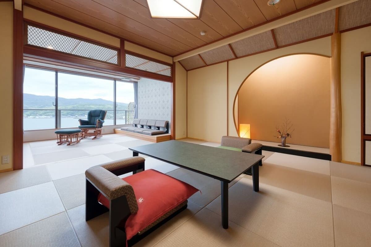 Une pièce avec un sol recouvert de tatamis, comprenant une table basse en tatami, un canapé et une vue sur l’extérieur.