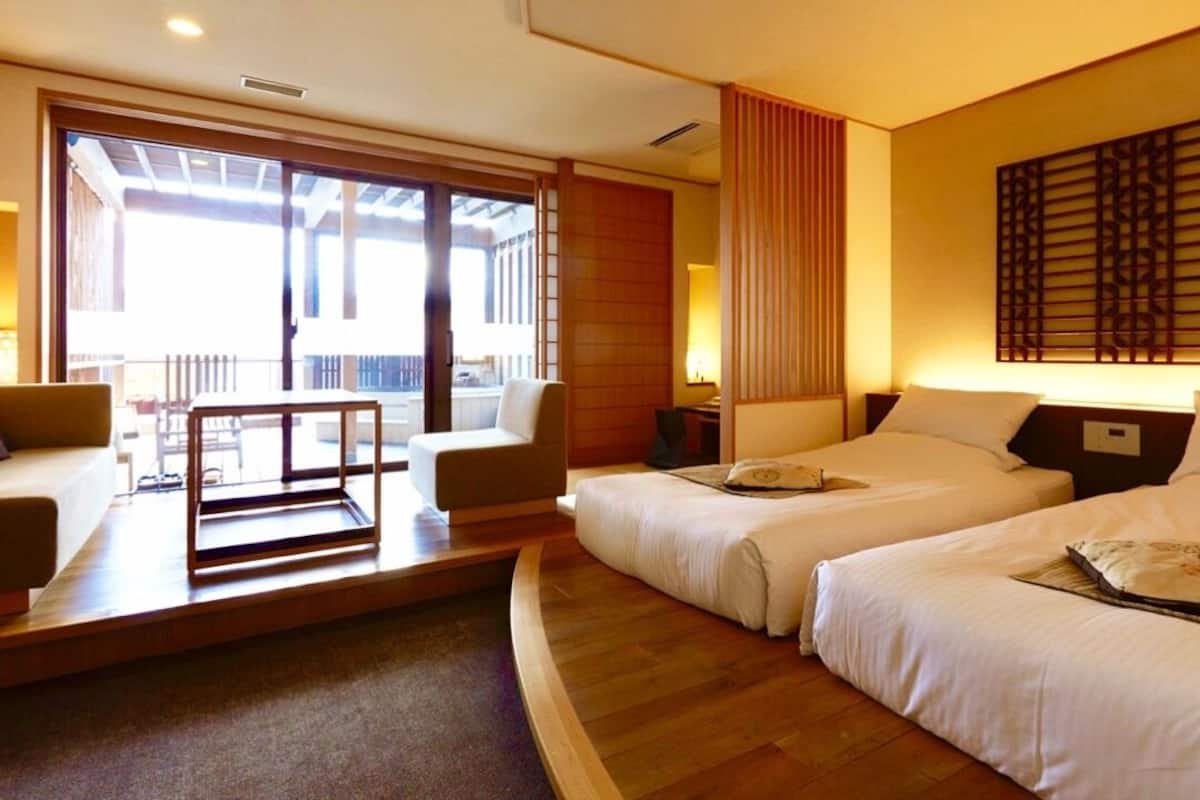 Une chambre d’hôtel avec deux lits, un canapé, une table et une vue sur l’extérieur.