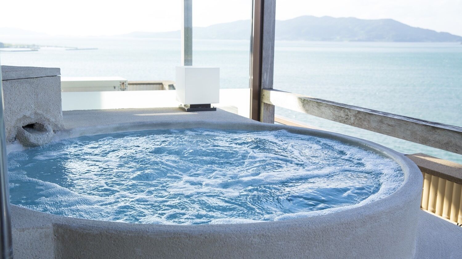 A hot tub with a view of the sea and mountains.