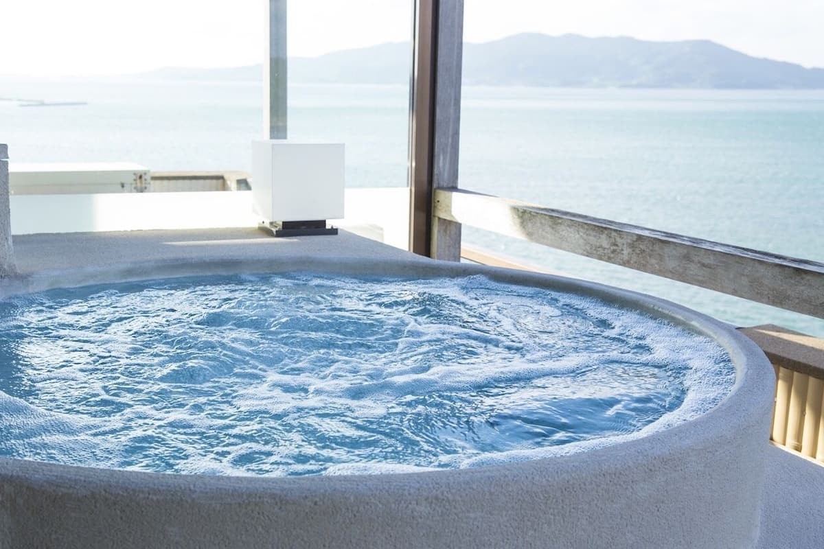 A hot tub with a view of the sea and mountains.