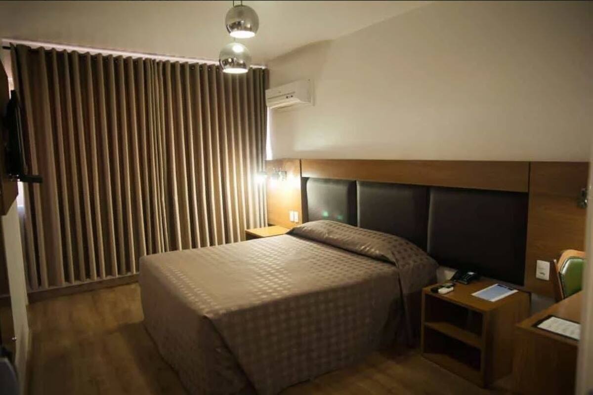 Ein Hotelzimmer mit Bett, Nachttisch, Lampe und Fernseher.