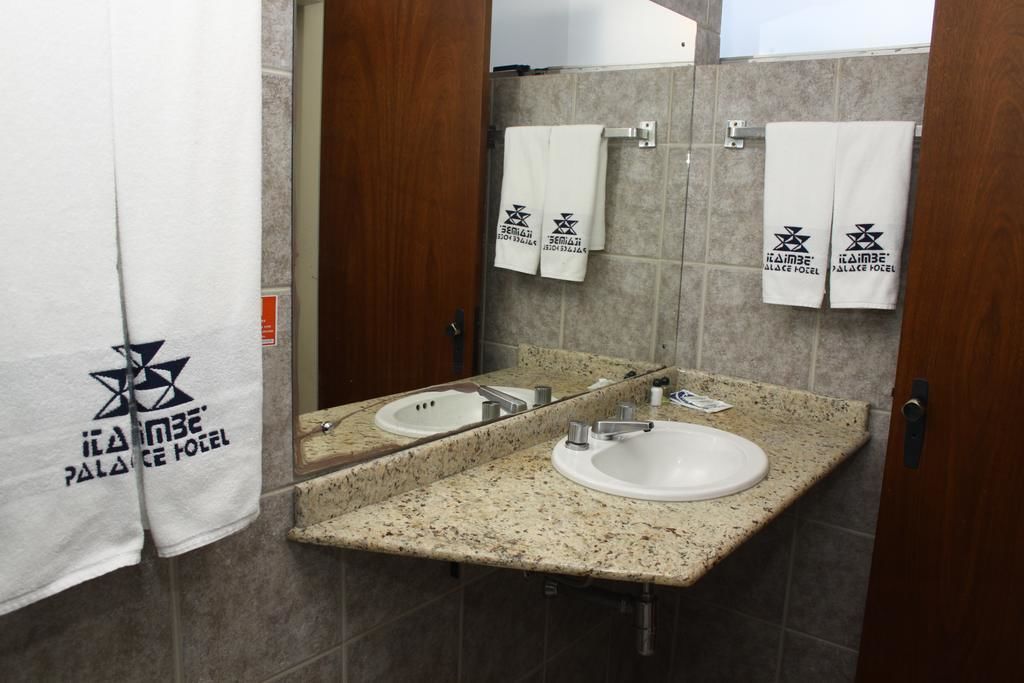 A bathroom with two sinks, a mirror, and towels hanging on a rack.