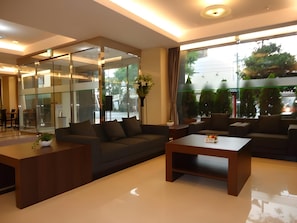 A modern hotel lobby with a sofa, coffee table, and a glass partition. - Shimonoseki Station Hotel (Shimonoseki)