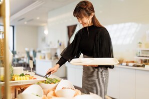A person serving food in a modern kitchen with white cabinets and a bright interior.