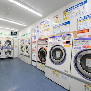 A laundromat with multiple washing machines and instructional signs.