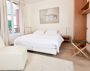 A bedroom with a bed, bedside table, lamp, and a window with curtains. - Hidden Bay Hotel (Cayeux-sur-Mer)