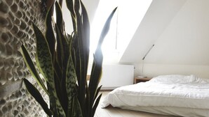 A bedroom with a bed, a potted plant, and a skylight. - Hidden Bay Hotel (Cayeux-sur-Mer)